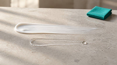 An opaque white gel swipe and a clear serum swipe side by side on pale stone, showing two acne actives used in one routine