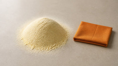 A soft mound of besan (gram flour) on pale stone beside a folded orange linen cloth
