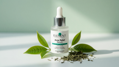 Fresh green tea leaves beside The Element 2% Salicylic Acid + 5% Niacinamide Acne Relief Serum on a soft pale-green background