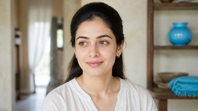 An Indian woman facing soft window light, with the sides of her nose, inner brows and hairline clearly lit — the areas where facial seborrheic dermatitis typically appears.