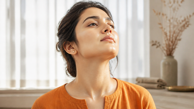 Indian woman in morning window light with chin lifted, face and neck evenly covered with freshly applied sunscreen