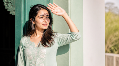 Indian woman shielding her face from bright sunlight with her raised hand