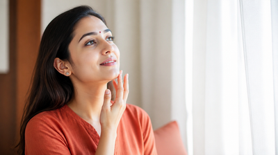 Indian woman tracing her fingertips along her upper lip and jawline in bright daylight