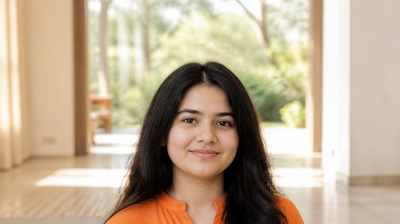 A young Indian woman with fresh, even, well-hydrated skin smiling softly in morning daylight, wearing an orange kurta