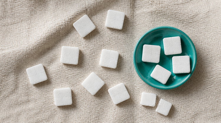 Square white camphor (kapur) tablets scattered on raw linen and in a teal-green ceramic dish