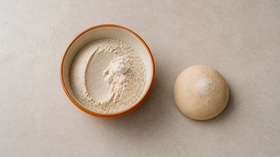 An orange bowl of whole wheat atta flour beside a ball of kneaded dough