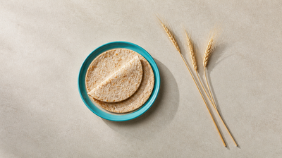 Whole-wheat rotis on a teal plate beside dry wheat stalks, illustrating gluten and acne