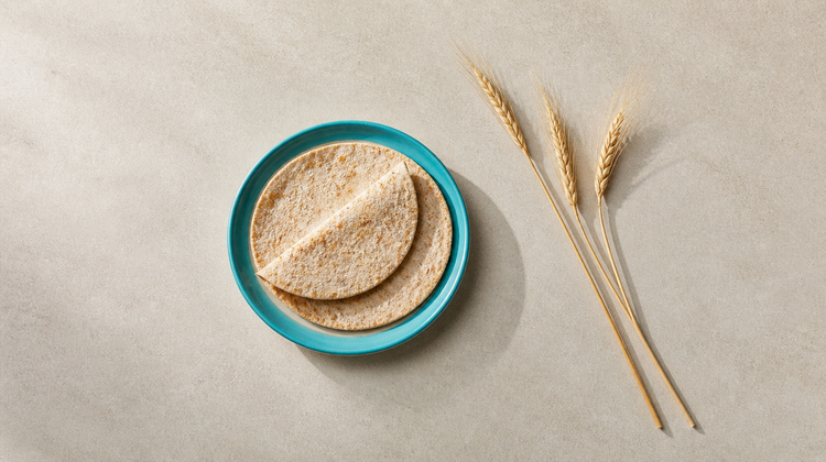 Whole-wheat rotis on a teal plate beside dry wheat stalks, illustrating gluten and acne