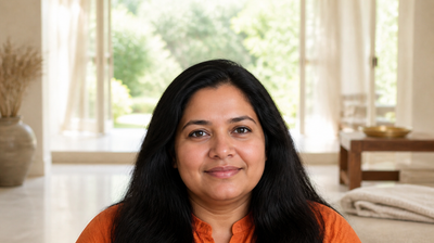 Indian woman in an orange kurta at home in morning light with calm, even-toned skin