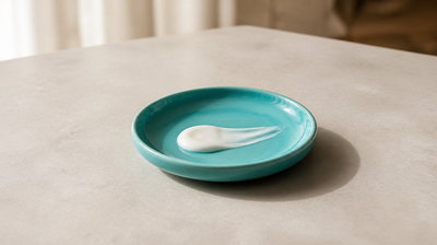 Swatch of white retinoid acne cream on a teal ceramic dish, illustrating trifarotene for face and body acne