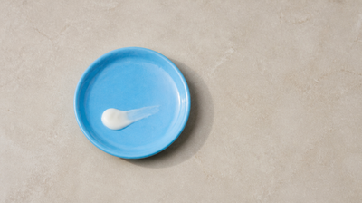 A small dab of white moisturising cream on a sky-blue ceramic saucer, for a guide to steroid cream side effects on the face