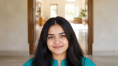 A young Indian woman with calm, clear skin in a teal kurta, standing at home in soft morning light