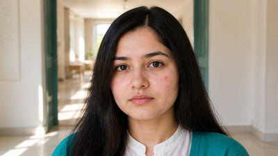 Young Indian woman with a healing acne spot and mild redness on one cheek, wearing a teal cardigan