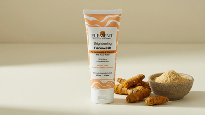Wild turmeric (kasthuri manjal) rhizomes and pale turmeric powder beside The Element Brightening Face Wash with 3% Niacinamide on a cream surface