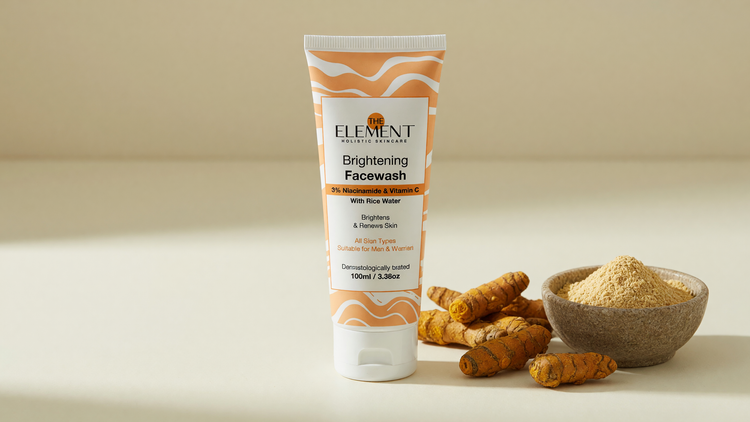 Wild turmeric (kasthuri manjal) rhizomes and pale turmeric powder beside The Element Brightening Face Wash with 3% Niacinamide on a cream surface