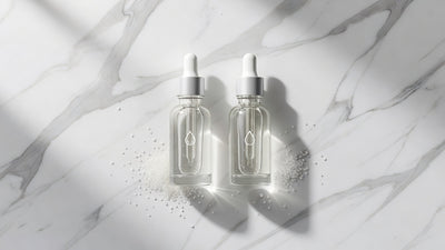 Two skincare serum bottles representing AHA and BHA chemical exfoliants on white marble surface