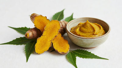 Fresh turmeric root cracked open beside golden paste and neem leaves, Ayurvedic skincare ritual