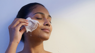 Indian woman gliding a cloth-wrapped ice cube along her cheekbone to de-puff her face