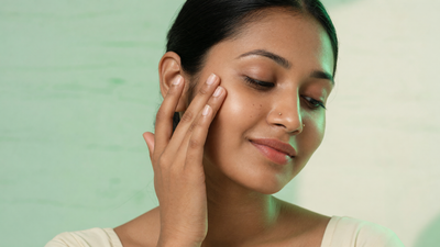 Indian woman with smooth, healthy skin gently touching her cheek