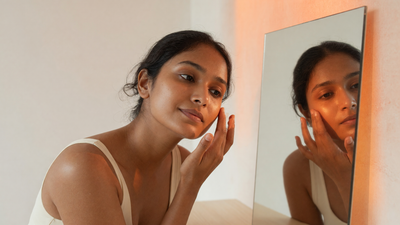 Indian woman with warm brown skin examining her skin type in a mirror