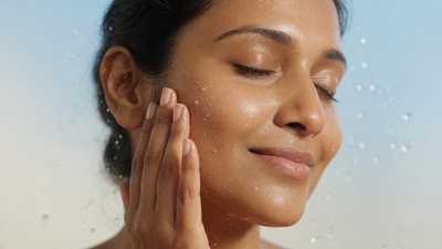 Indian woman with dewy hydrated glowing skin gently touching her cheek
