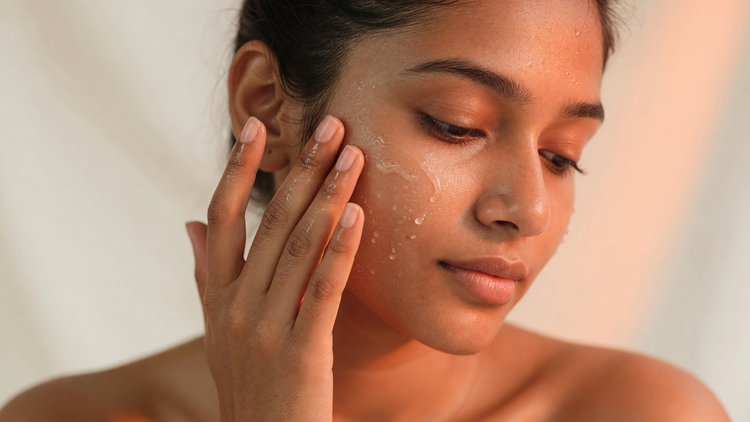 Indian woman pressing a face serum into her cheek with her fingertips