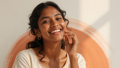 An Indian woman smiling confidently, celebrating her natural warm-brown, glowing skin tone.