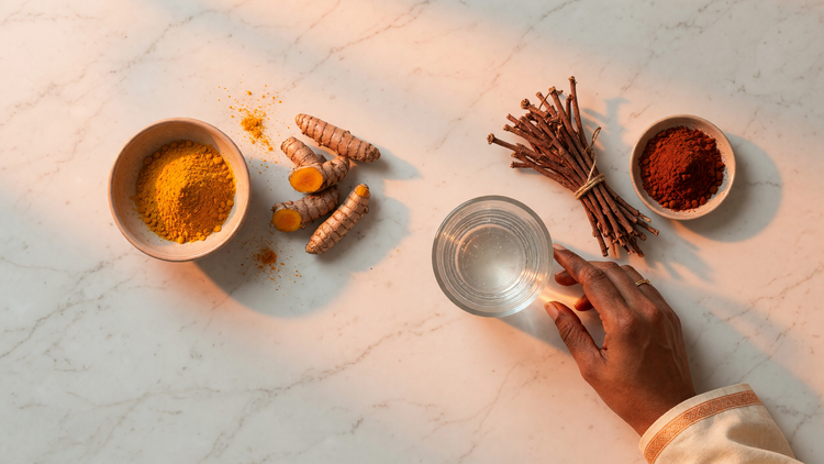 Ayurvedic flat-lay comparing turmeric powder and root with manjistha (Rubia cordifolia) roots and red powder beside a glass of water.