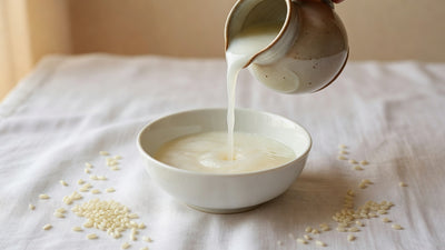 Milky rice water poured from ceramic jug into bowl with rice grains, Japanese beauty ritual