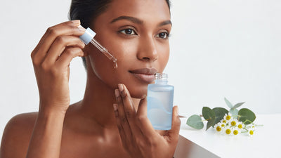 Indian woman applying hydrating serum to her cheek for dry skin care routine