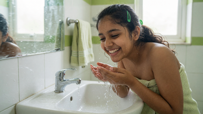 Indian teenage girl washing her face at a bathroom basin as part of a simple skincare routine